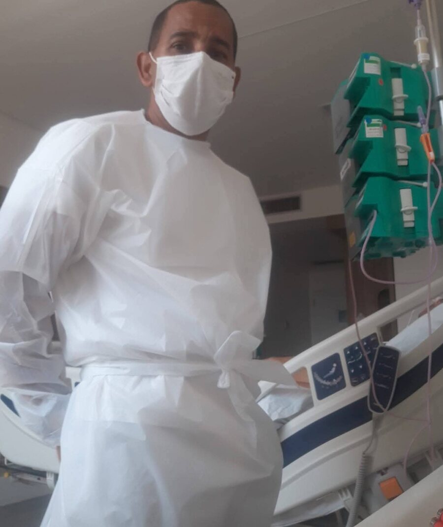 Profissional da Deferrone Home Care paramentado ao lado de um leito hospitalar